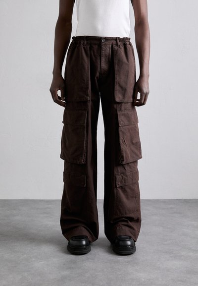 Pantaloni cargo marroni in cotone con vestibilità ampia, dotati di molteplici tasche grandi, vita elastica e dettagli di cucitura visibili.