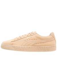 Sneaker beige Puma Suede a basso profilo con chiusura con lacci e suola testurizzata, vista dal lato esterno.