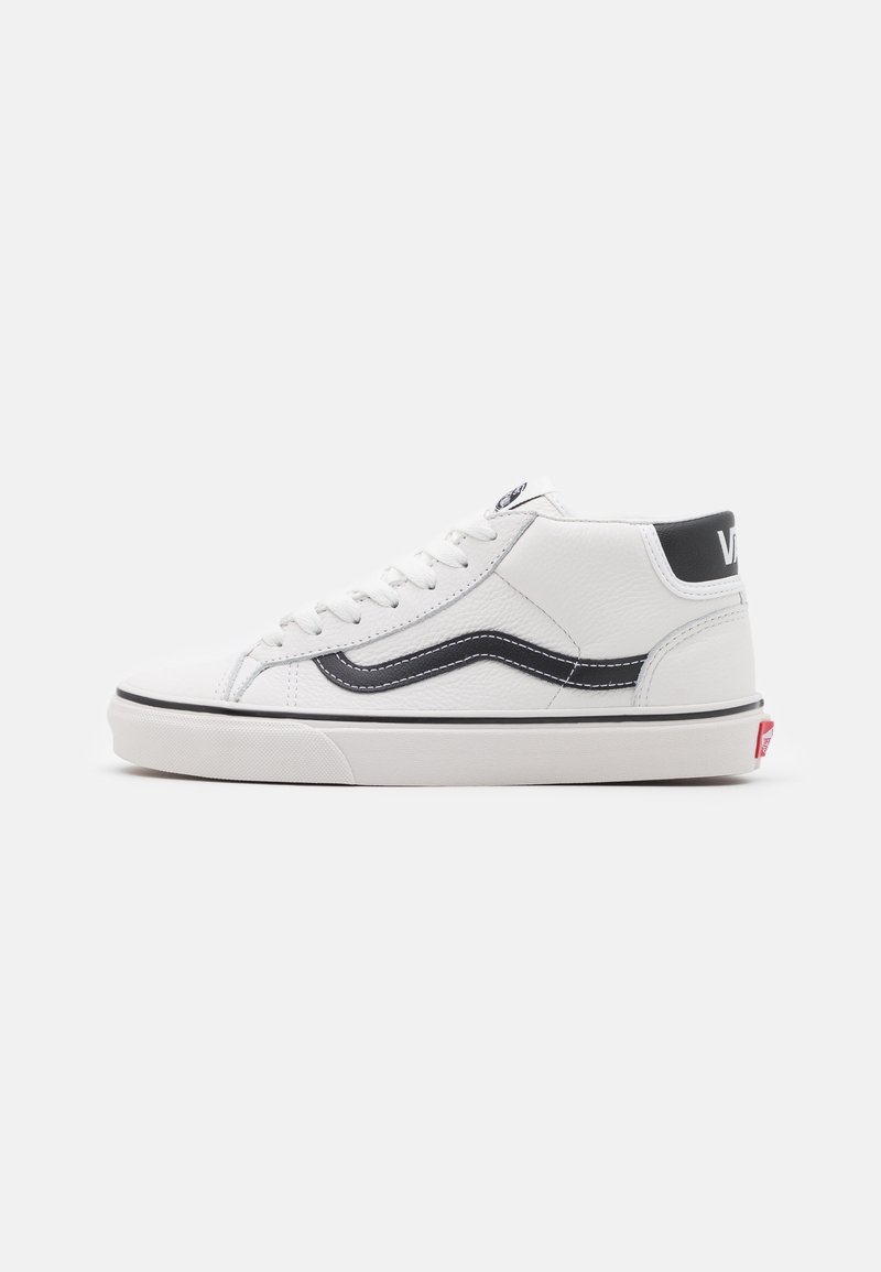 Baskets montantes blanches Vans avec une bande latérale noire, des lacets blancs et un logo rouge à l'arrière de la semelle sur un fond clair.