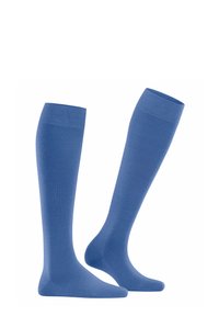 Calze blu chiaro al ginocchio esposte, con una superficie liscia e una parte superiore rinforzata, posizionate in diagonale su uno sfondo bianco.