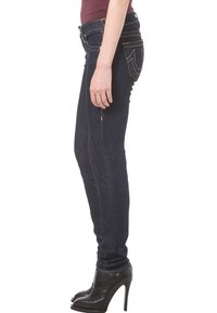 Smala mörka jeans i denim med framträdande sömmar, sidofickor och dragkedja. Bärs med svarta högklackade skor.