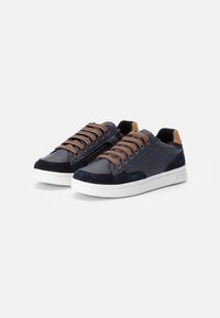 Zapatillas navy con material de malla y ante, suela blanca plana, cordones marrones y detalles de cremallera lateral.