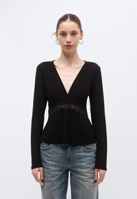 Top negru cu mâneci lungi, având un decolteu adânc în V și un detaliu din dantelă pe talie. Materialul este neted, cu un corsaj mulat și tiv evazat.
