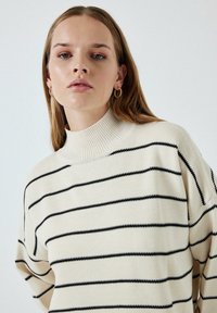 Kreemikattega sviiter mustade horisontaalsete triipudega, ribatud kõrge kaelusega ja langetatud õlgadega. Sujuv tekstuur ja lõdva istuvusega.