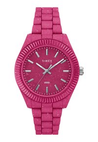 Reloj Timex rosa con correa de silicona texturizada, esfera redonda, bisel estriado, marcadores de hora plateados y agujas a juego. Diseño resistente al agua.
