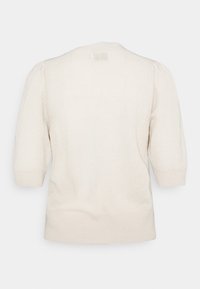 Ljus beige stickad tröja med korta puffärmar, rund halsringning, ribbade mudd och nederkant, med en texturerad tygkvalitet och sömlös baksidedesign.