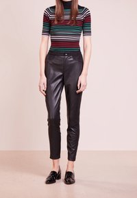 Svart läderbyxor med slim fit, med en framknappsstängning och två fickor. Matcher med en flerfärgad randig ribbad topp.