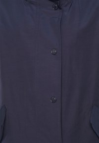 Marineblauwe lichtgewicht jas met een hoge kraag, knopen aan de voorkant en zijzakken, uitgerust met een gladde textuur en een minimalistisch ontwerp.