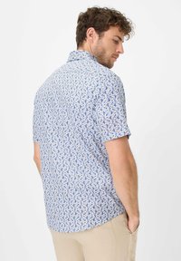 Korte mouw shirt in lichtblauw met een bloemenpatroon met marineblauwe en gele accenten; button-down kraag en gebogen zoom.