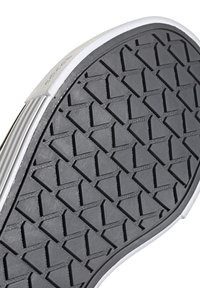 Semelle de chaussure en caoutchouc noir avec un motif en losange et un accent blanc sur le bord, présentant des rainures pour la traction et la stabilité.