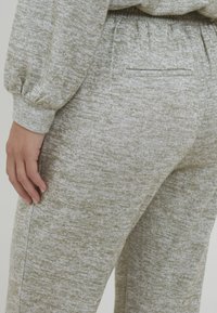 Súprava lounge oblečenia v olivovej zelenej farbe, vyrobená z mäkkej, textúrovanej látky. Nohavice majú slim fit strih a malý detail v podobe zadnej vrecka.
