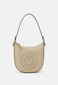 Sac à main en cuir beige de forme semi-circulaire, avec un design de logo perforé et un contour noir contrastant. Bandoulière unique incluse.