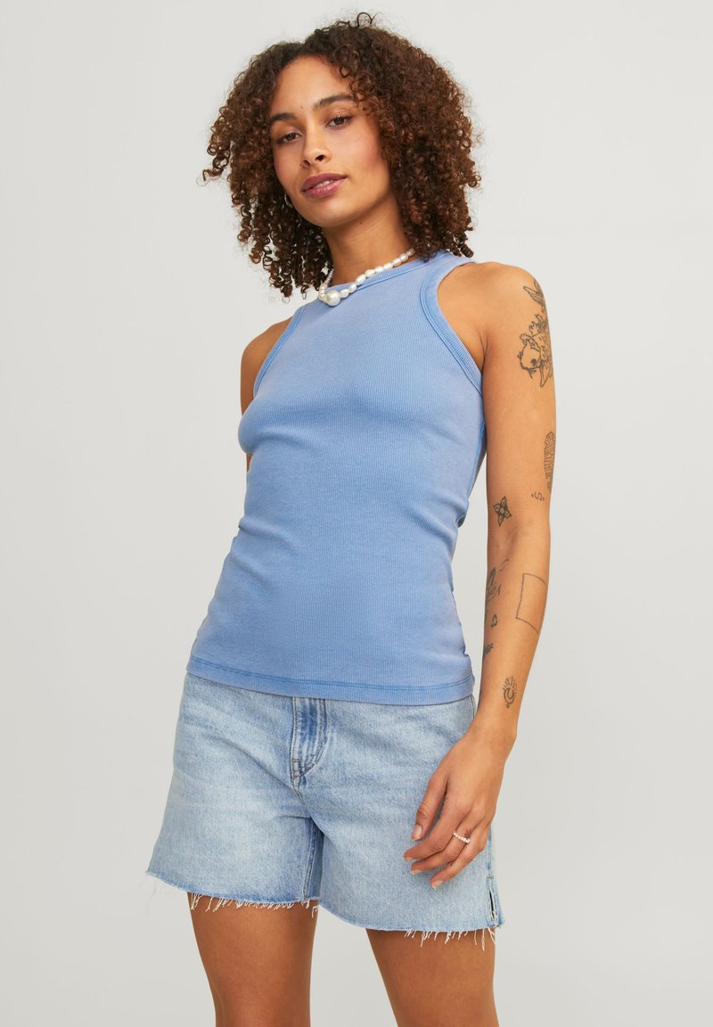 Top de malha azul-claro com um design justo e decote redondo, combinado com uns calções de ganga claros com bainhas desfiadas.