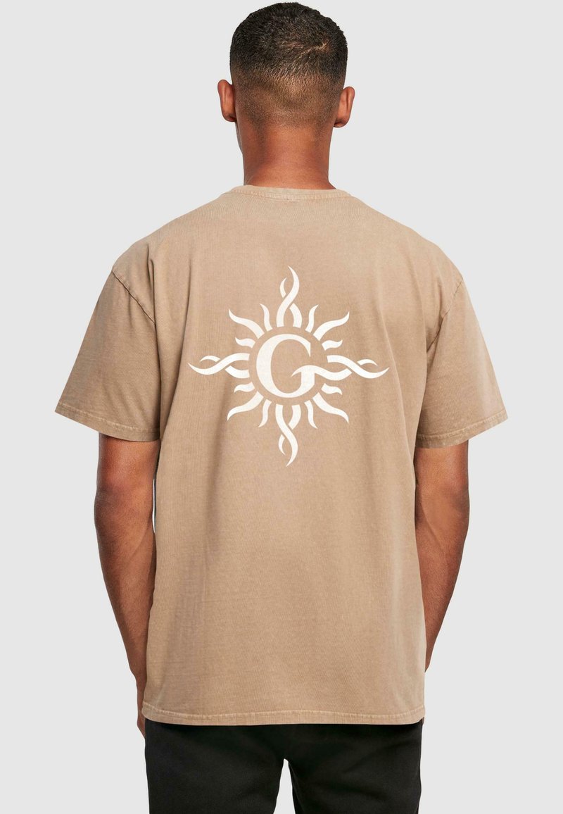 Tan bomulds t-shirt med et hvidt sol design med svulmende former på ryggen. Rund hals, korte ærmer, afslappet pasform. Struktureret finish.