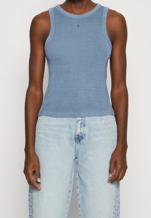 Niebieski prążkowany top na ramiączkach z okrągłym dekoltem i wąskimi paskami, z małym logo na piersi. W zestawie z jasnoniebieskimi dżinsami.