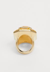 Gold-tone ring featuring a geometric design with a central amber-colored stone, smooth surface, and a wide band.