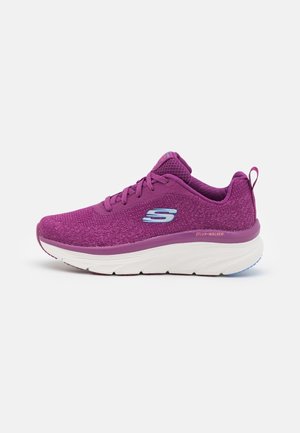 Chaussure de sport violette avec une tige en maille texturée, lacets à l'avant, col rembourré et une semelle blanche épaisse. Présente un logo sur le côté et le talon.