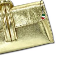 Sac à main en or métallique avec texture lisse, design pliable, accents de double sangle et attache de charme drapeau italien.