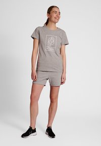 Grå bomulls t-shirt och shorts-set med en vit geometrisk grafik. Tyget ser mjukt ut med en avslappnad passform. Svarta träningsskor fulländar looken.