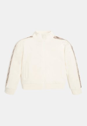 Veste zippée crème avec un col haut, dotée de rayures latérales texturées et de deux poches avant. Tissu doux avec des poignets côtelés.