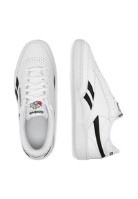 Valged nahast tennisetossud mustade aktsentidega, perforeeritud varvas, lapikud paelad ja tekstureeritud tallad; logo keelel ja küljel.