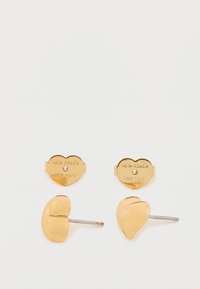 Zlaté kovové náušnice ve tvaru ledviny a srdce. Hladký povrch s vyrytým názvem značky na zadní straně.