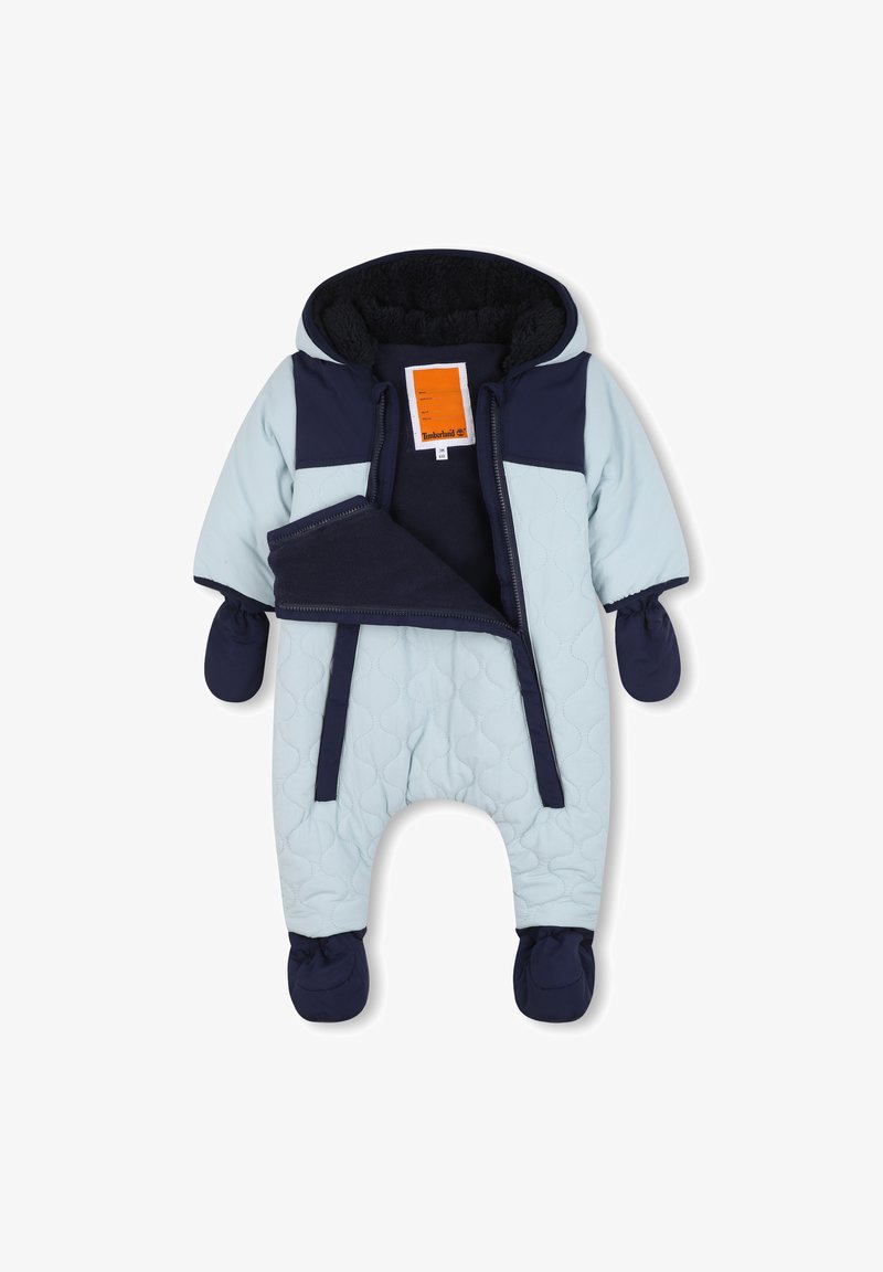 Svijetloplavi zimski kombinezon s tamnoplavim detaljima, kapuljačom, zatvaranjem na patentni zatvarač i odvojivim rukavicama. Mekana unutarnja podstava za dodatnu toplinu.