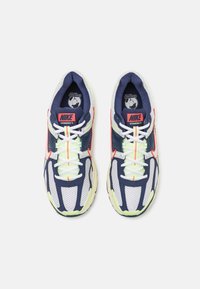 Ténis Nike Vomero 5 com parte superior em malha e sintético, nas cores azul-marinho e branca, com detalhes em neon, sola de borracha grossa e sistema de atacadores.