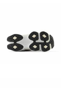 Suela de goma negra con patrones hexagonales, mediasuela blanca y marca visible; cuenta con ranuras flexibles para tracción y soporte.