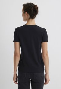 Black short-sleeve t-shirt displayed from the back, made of soft fabric with a round neckline. Simple design, no patterns or accents visible.