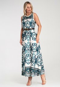 Maxi sukienka w kolorze białym z turkusowym, ozdobnym wzorem, bez rękawów, z zaznaczoną talią za pomocą brązowego pasa, zwiewna spódnica z bogato zdobionym dołem.