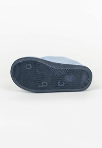 Suela de zapato de tela azul con goma negra texturizada, que presenta un patrón ondulado y un logo embosado. Bordes curvados y múltiples patrones de agarre.
