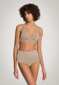 Zestaw biustonosza w kolorze nude i majtek z wysokim stanem, wykonany z gładkiego materiału o prążkowanej fakturze. Posiada dekolt w serek i szerokie ramiączka.