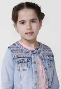 Denim jakna v svetlo modri barvi, ki ima teksturiran vezen vzorec na ramenih, gumbne zaponke in dva sprednja žepa.