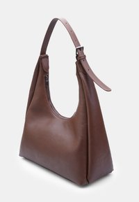 Braune Leder-Schultertasche mit einer geschwungenen Form, einem Reißverschlussfach und einem verstellbaren Trageriemen. Glatte Textur mit minimalistischem Design.