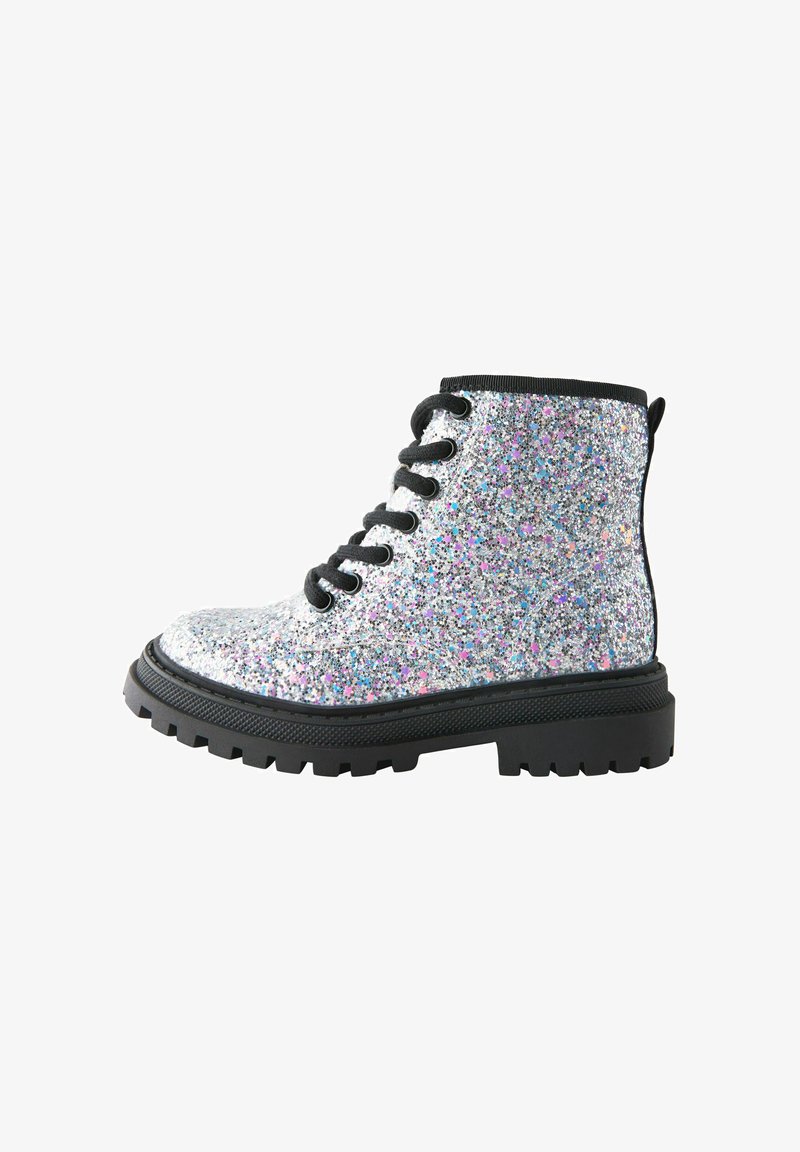 Glitzernder silberner Kampfstiefel mit schwarzer dicker Sohle und schwarzen Schnürsenkeln, Seitenansicht auf weißem Hintergrund.