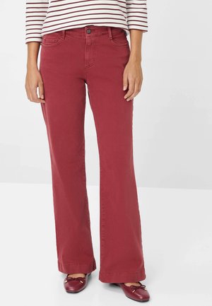 Red flared pants made of cotton blend fabric, featuring a front button closure, five pockets, and a smooth texture.