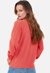 Pull en maille corail avec une coupe décontractée, épaules tombantes et poignets côtelés. Vue de dos montrant une texture lisse et des manches longues.