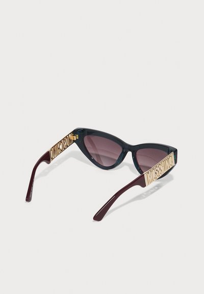 Kattögon-solglasögon med gradientmörka linser, svarta plastbågar och bordeauxfärgade armar som har en guld Moschino-logotyp.
