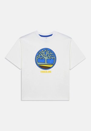 T-shirt blanc à manches courtes avec un grand logo d'arbre bleu et vert à l'intérieur d'un cercle, et le texte "TIMBERLAND" en jaune en dessous.