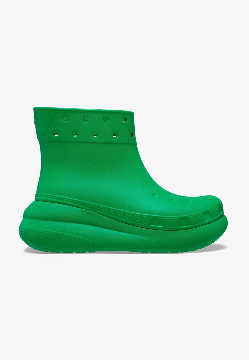 Bottine verte en caoutchouc avec des trous perforés et une semelle épaisse et rembourrée, conçue pour la résistance à l'eau et le confort.