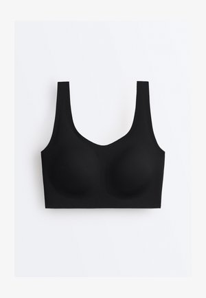 Črni brezžični nedrček z širokimi naramnicami, brezšivnimi košaricami in gladkim, raztegljivim materialom na enostavni belem ozadju.