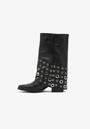 Zwarte leren enkellaars met een vierkante neus, voorzien van grote zilveren oogjes die in een patroon langs de onderzijde zijn geplaatst. Platte hak.