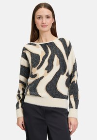 Gebreide trui met een golvende dierenprint in zwart, beige en crème. Zachte, textuurstof met een bootnek en geribde manchetten.