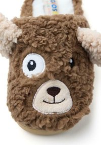 Pantofole marroni in peluche a forma di faccia di orso, dotate di occhi, naso e bocca sorridente ricamati, e morbidi orecchi color crema.