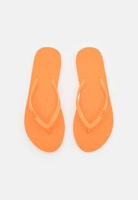 Tongs orange avec semelle texturée, bride flexible et fines lanières. Design minimaliste adapté à un usage décontracté.