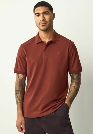 Braunes Poloshirt mit kurzen Ärmeln aus glattem Stoff, mit einem Kragen, einer dreiknöpfigen Leiste und einem kleinen gestickten Logo auf der Brust.