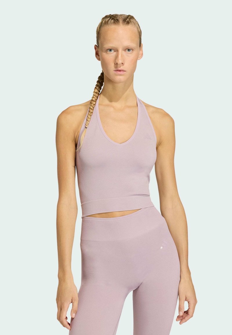 Top deportivo corto de color púrpura claro con escote en V profundo y textura acanalada, combinado con leggings a juego de talle alto. Diseño liso y ajustado.