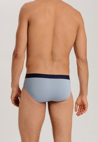 Slip da uomo in tessuto azzurro chiaro, con elastico navy decorato con logo. Vestibilità elegante e texture liscia.