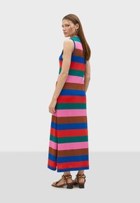 Randig maxiklänning med breda horisontella ränder i blått, rött, grönt, rosa och brunt; ärmlös design med en mjuk textur.